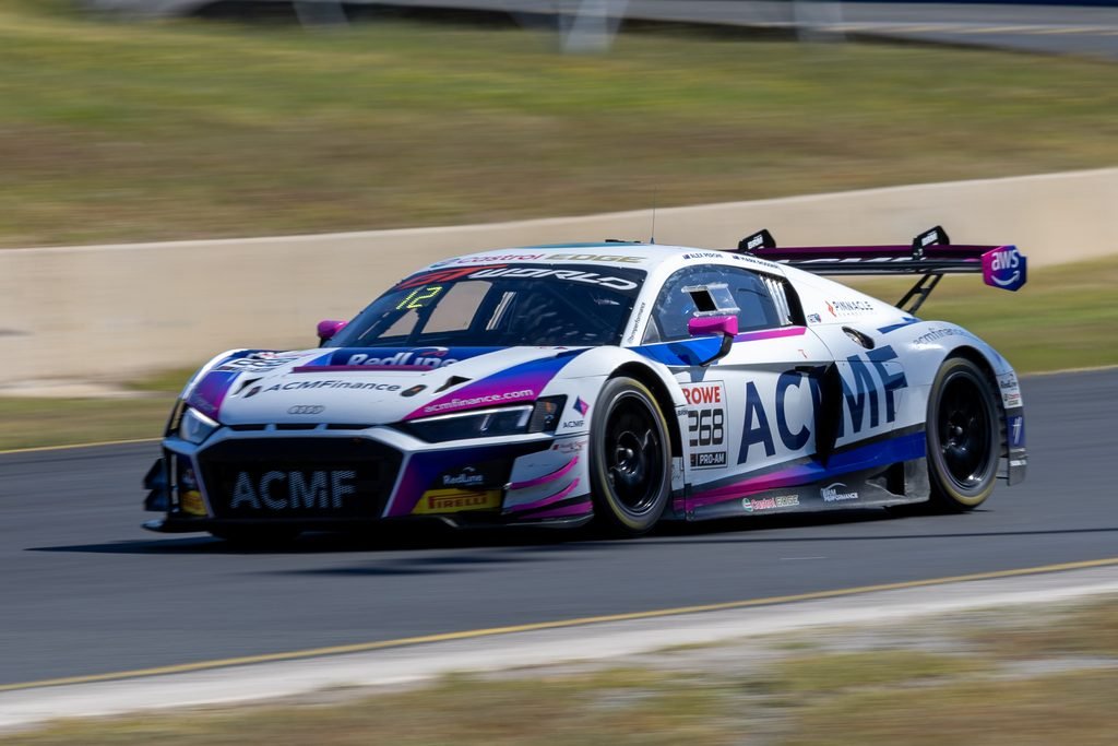 0I1A0769 • Sports Rewind Media White ACME race car with pink and blue livery speeding along a racetrack, sponsor logos visible on the body and rear wing.