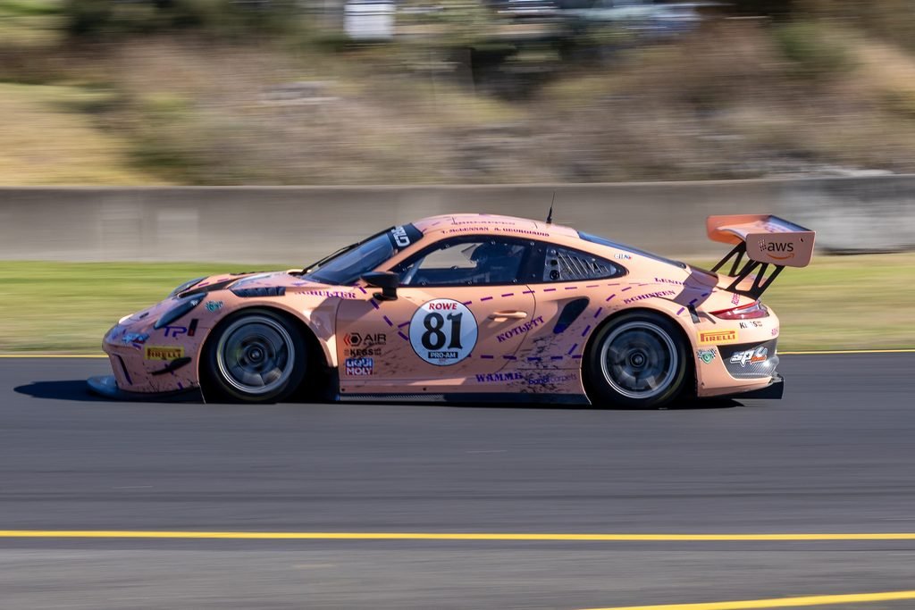 0I1A2481 • Sports Rewind Media Pink race car number 81 speeding on a track with sponsor decals and a wing at the rear, motion blurred background.