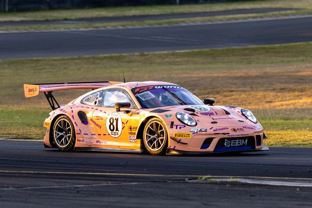 _I1A1601 • Sports Rewind Media Pink race car with the number 81 on its door, shown in a front-left profile on a race track with a large rear wing and sponsor decals all over the body.