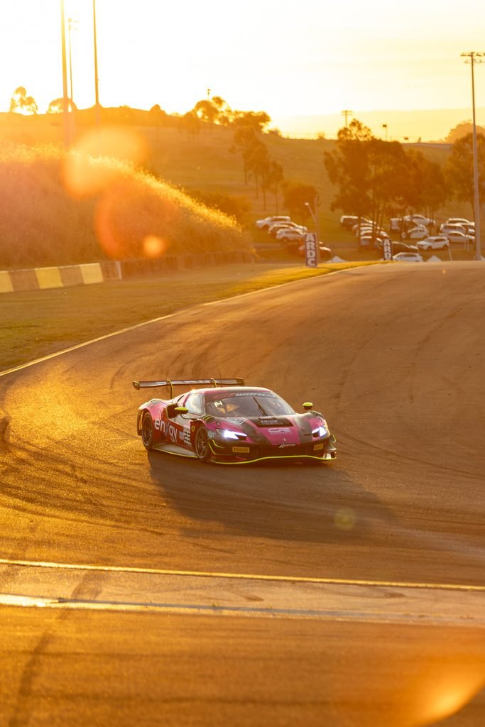 _I1A1654 • Sports Rewind Media Race car on a curved track during sunset, pink sponsor livery and a warm golden glow across the scene.