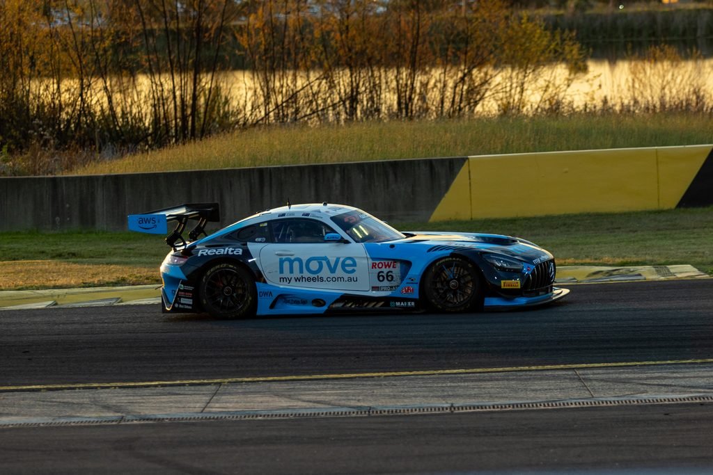_I1A1682 • Sports Rewind Media Blue race car with sponsor logos (Move my Wheels) and number 66 on a track beside a yellow barrier, in an outdoor setting.