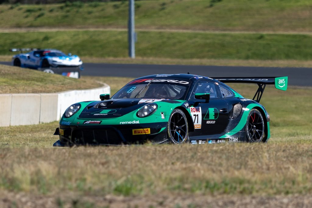 _I1A2416 • Sports Rewind Media Green and black race car speeding on a track with another blue racer in the background on a grassy circuit.