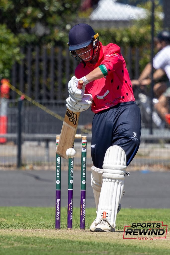 _I1A4737 • Sports Rewind Media Cricketer in a pink shirt and helmet playing a shot with a bat near the wickets on a cricket field.