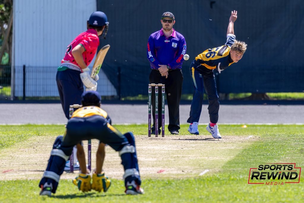 _I1A4894 • Sports Rewind Media Cricket match scene with a bowler delivering toward the batsman near the wickets as the umpire watches.