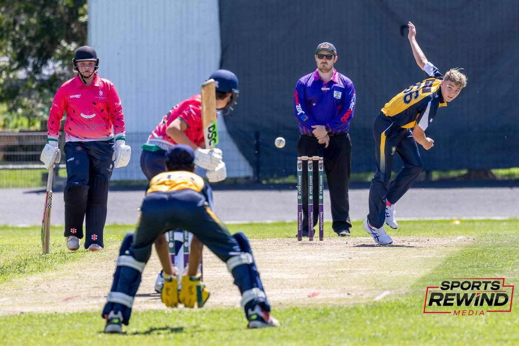 _I1A4908 • Sports Rewind Media Cricket match scene with players at the crease: a pink-wearing wicketkeeper, a batsman facing the ball, and a bowler in yellow and blue delivering the ball, with a SPORTS REWIND logo in the corner.